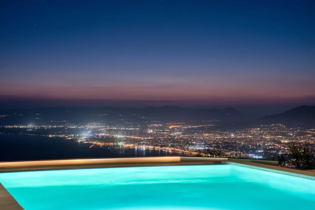 Piscine privée la nuit face aux lumières de Kalamata